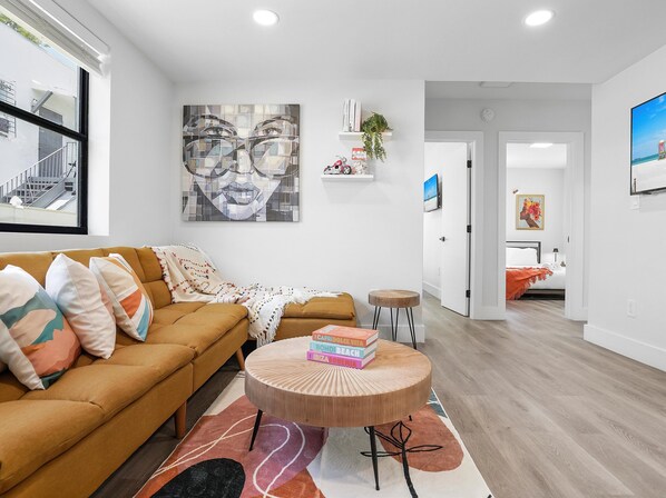 A modern living room with a sofa, a round coffee table, and a large abstract painting on the wall.