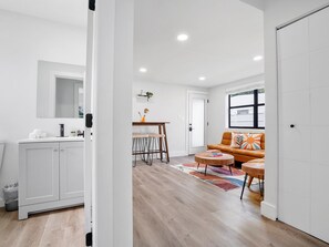 Un salon moderne avec un canapé, une table basse et un coin repas équipé de tabourets.