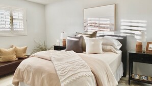 A bedroom with a bed, bedside tables, a mirror, and a window with a view. - The Courtyard on Pio Decimo  (Tucson)