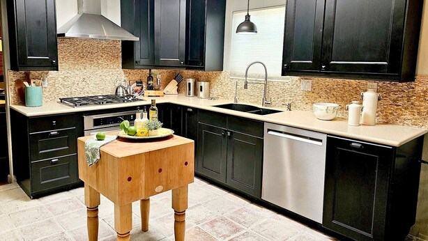 A modern kitchen with dark cabinetry, a central island, and a dishwasher. - The Courtyard on Pio Decimo  (Tucson)