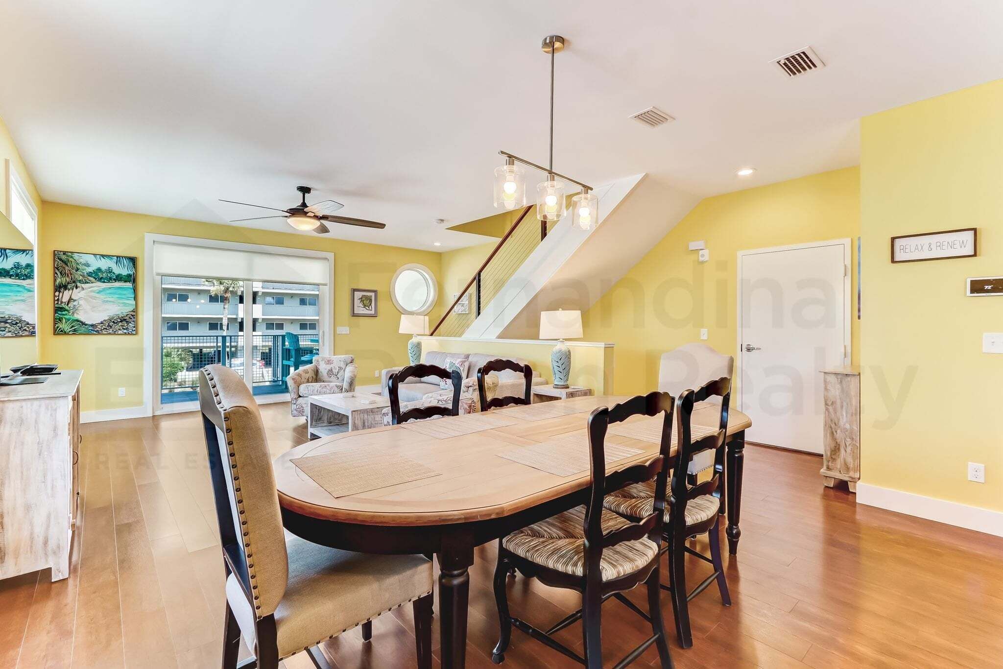 Un comedor amplio con techo alto, una escalera y vistas al exterior.