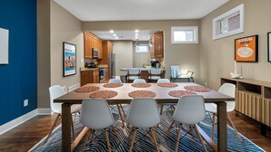 Una cocina moderna con armarios de madera, una isla central y una zona de comedor con una mesa grande y sillas.