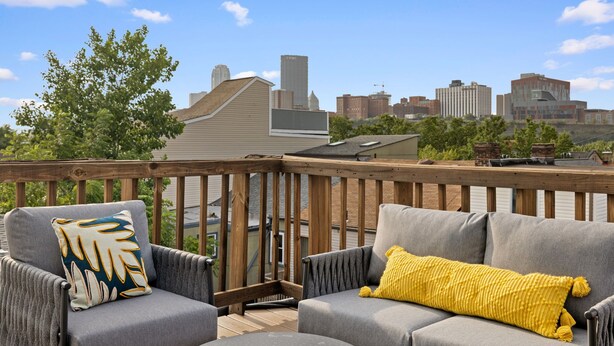 Una terraza con dos sofás grises y cojines amarillos, con vistas a un horizonte urbano.