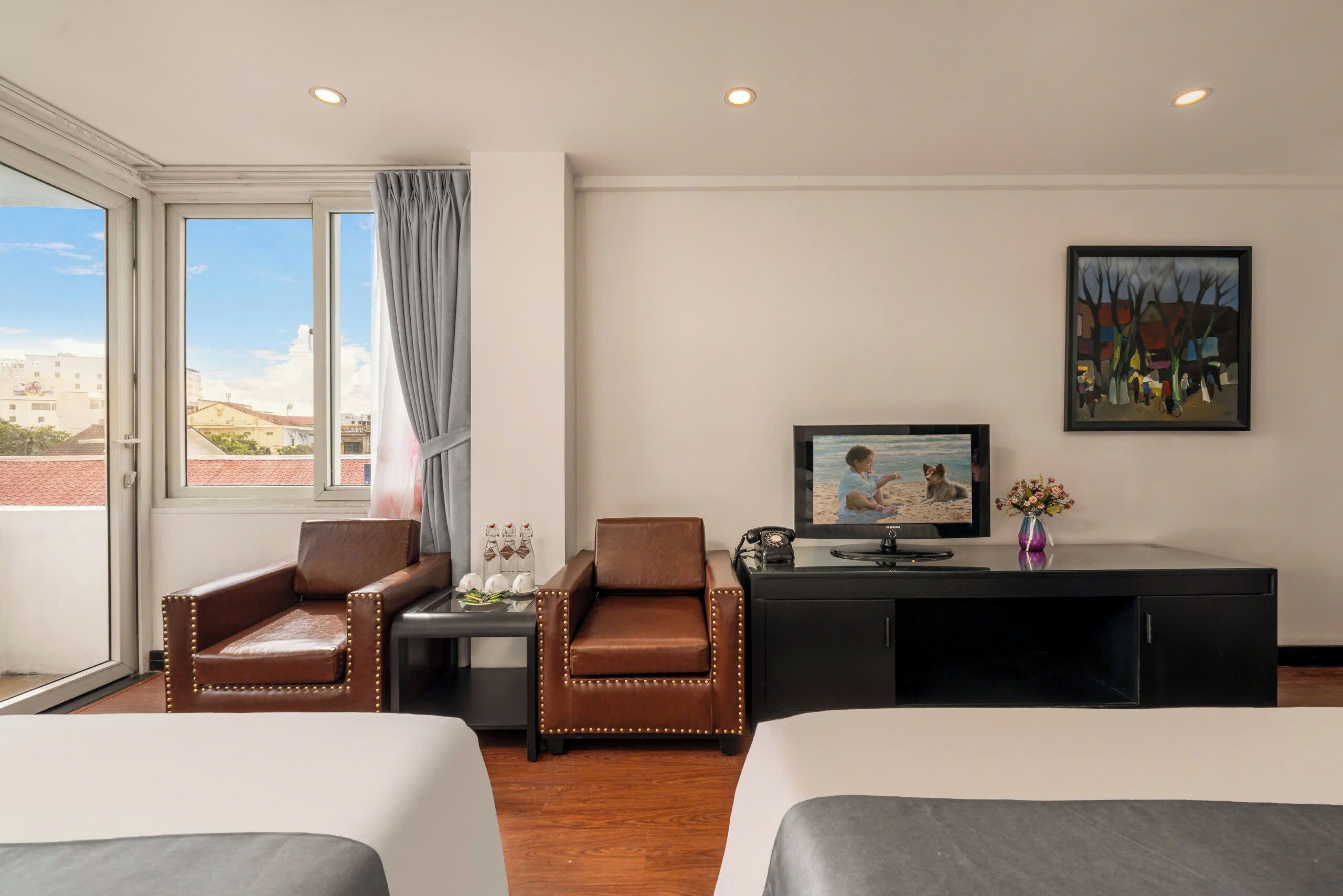 A hotel room with two beds, a desk with a television, a chair, a window with curtains, and a painting on the wall.