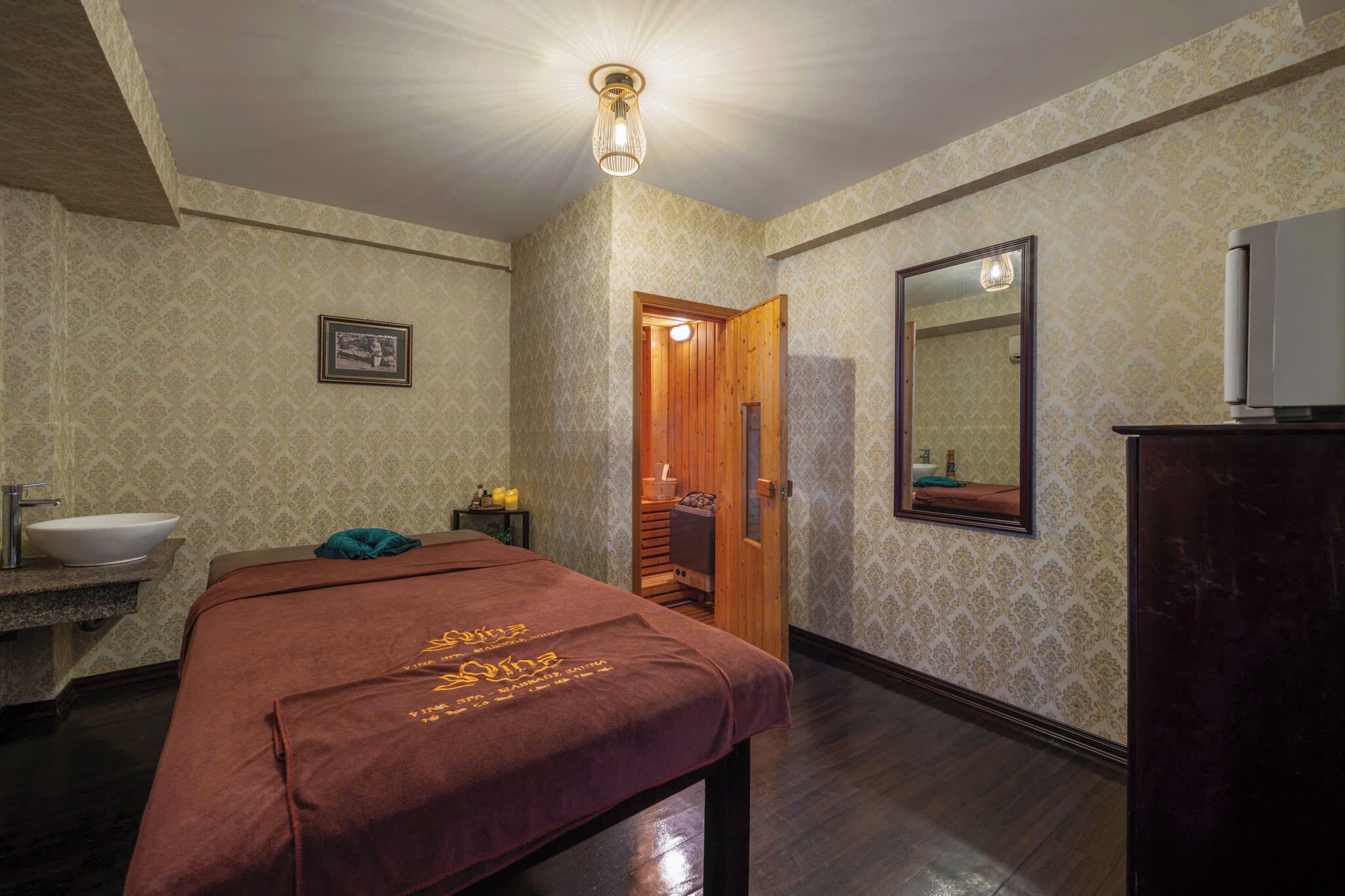 Una habitación de hotel con una cama, una puerta de madera, un espejo, un lavabo y un armario.