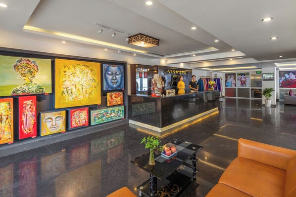 A hotel lobby with a reception desk, artwork on the walls, and seating areas. - Vina Spa Hotel (Hue)