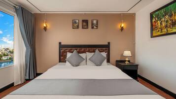 Una habitación de hotel con una cama grande, una mesita de noche con una lámpara y un cuadro en la pared.