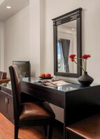 Un escritorio moderno con una silla, un florero con flores y un espejo en la pared.