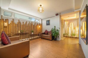 Un interior moderno con suelo de madera, un sofá, un banco y una pared decorada con elementos verticales de bambú.