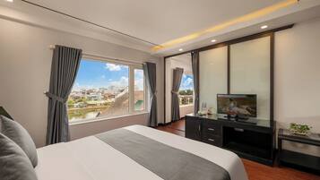 Una habitación de hotel moderna con una cama grande, un televisor de pantalla plana, un escritorio y vistas a la ciudad a través de la ventana.