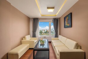 Una sala de estar moderna con dos sofás, una mesita de centro y vistas a un paisaje urbano a través de amplias ventanas.