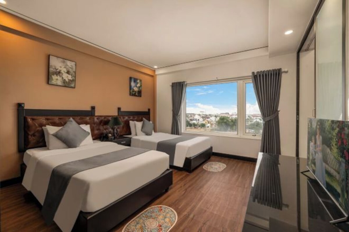 A hotel room with two beds, a large window with a view, and a flat-screen TV.