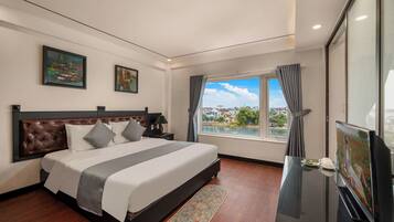A modern hotel room with a large bed, a TV, and a view of the city.