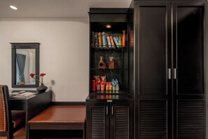 A hotel room with a large wardrobe, a vanity with a mirror, and a seating area with a bench. - Vina Spa Hotel (Hue)