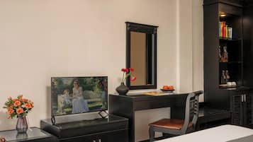 Habitación moderna con escritorio, silla, televisor y estantería.