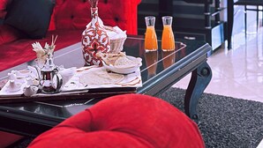 Uma sala de estar moderna com um sofá vermelho, uma mesa de centro com petiscos, um vaso e uma TV exibindo "NETFLIX".