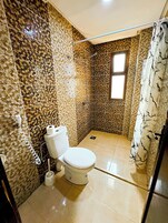 Un baño con inodoro, ducha y paredes con diseño.