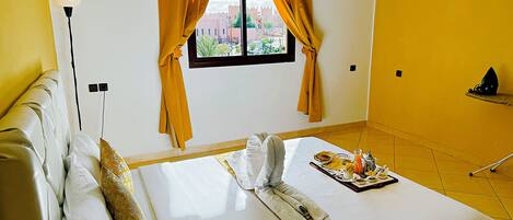 Habitación de hotel con cama, ventana con cortinas, mesita de noche y vistas a la ciudad.
