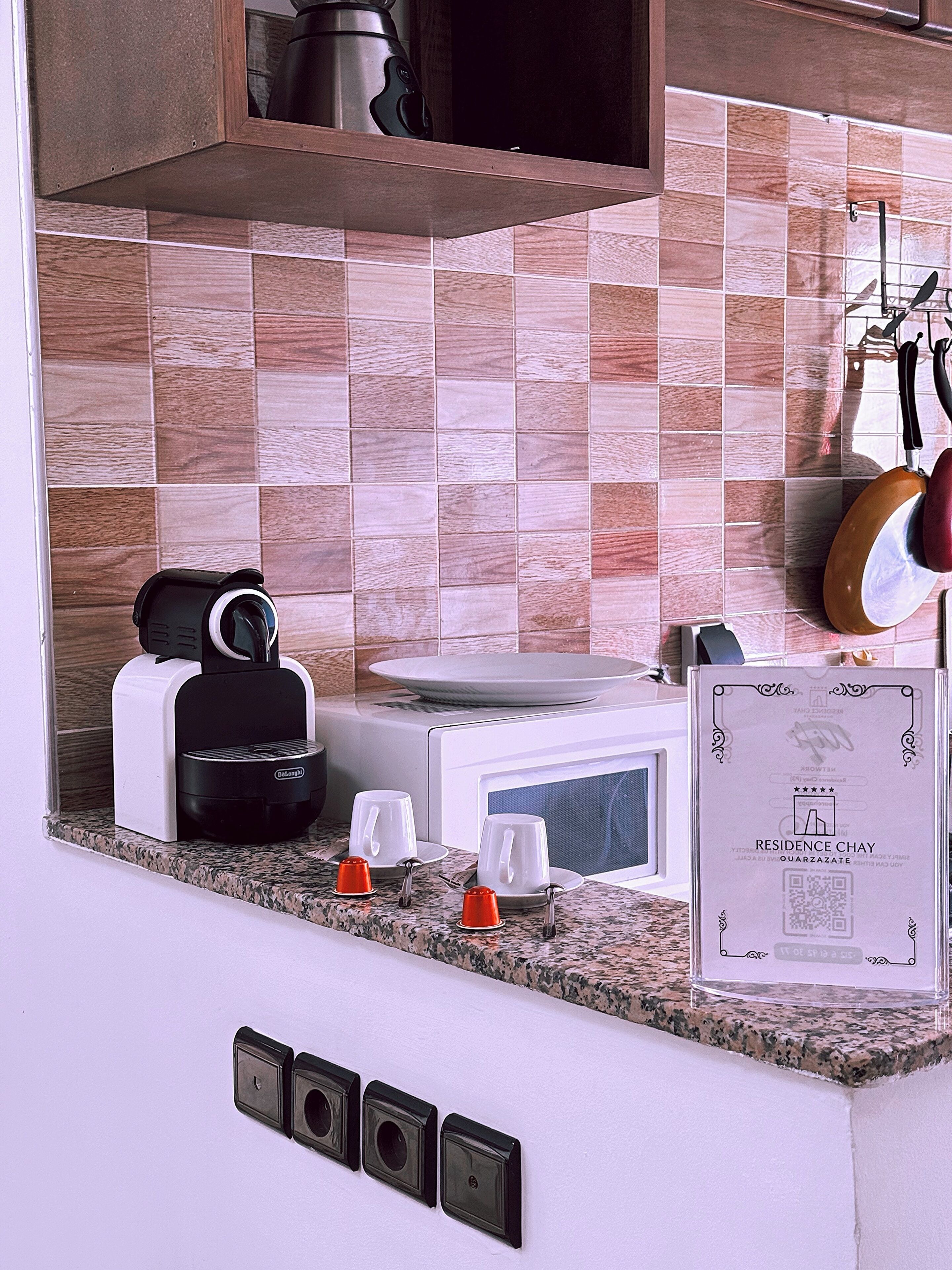 A kitchen with a microwave, toaster, and a QR code sign on the counter.