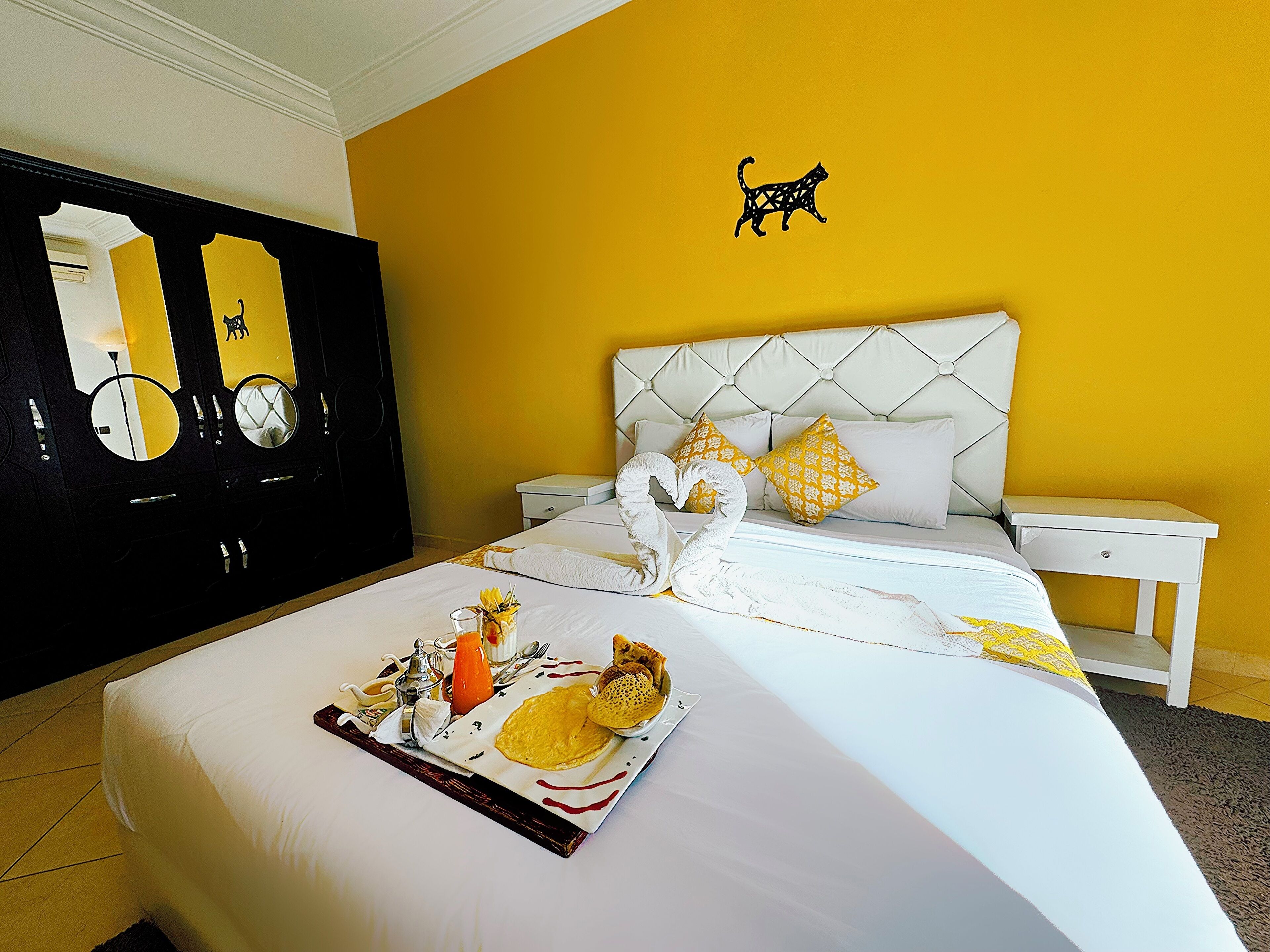 Una habitación de hotel con una cama, una mesita de noche, un espejo y un adorno en la pared.
