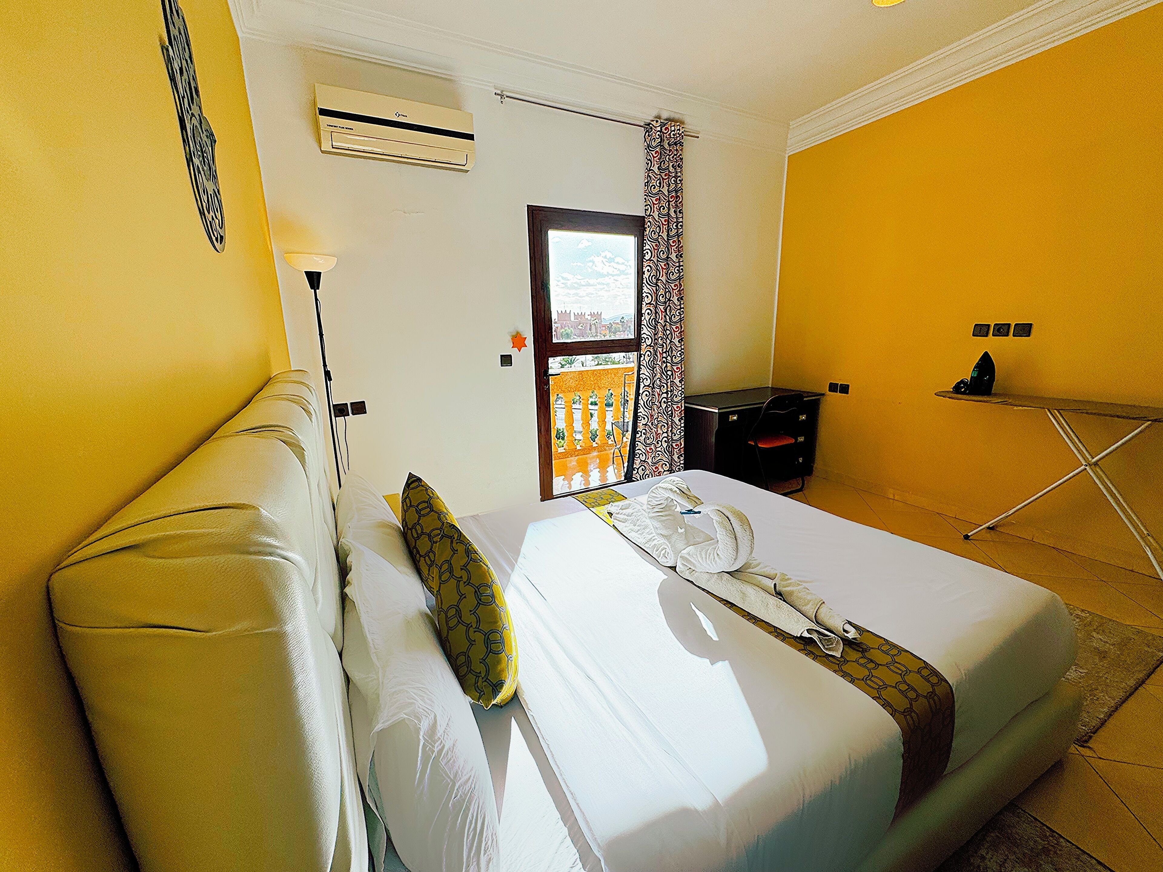 Habitación de hotel con cama, escritorio, aire acondicionado y ventana con cortinas.