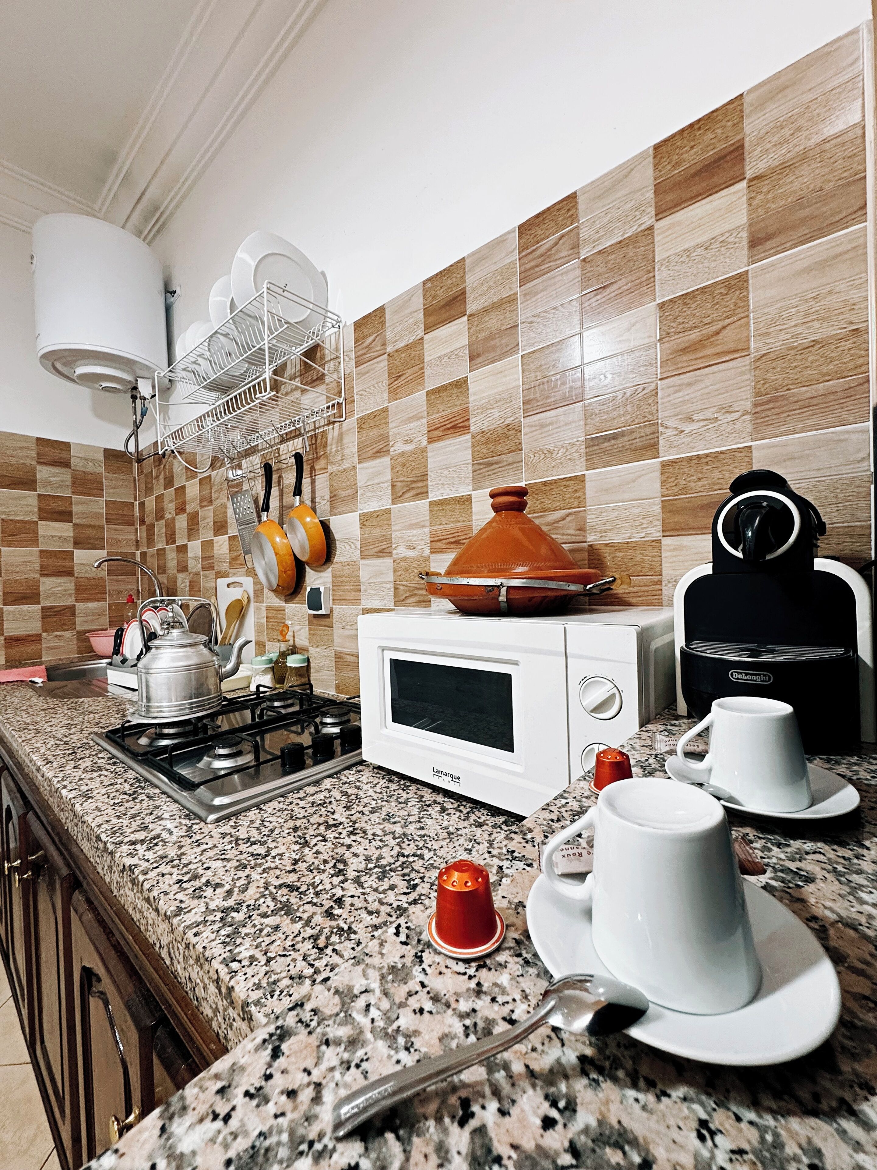 A kitchen with a gas stove, a microwave, a coffee maker, and various kitchen utensils.