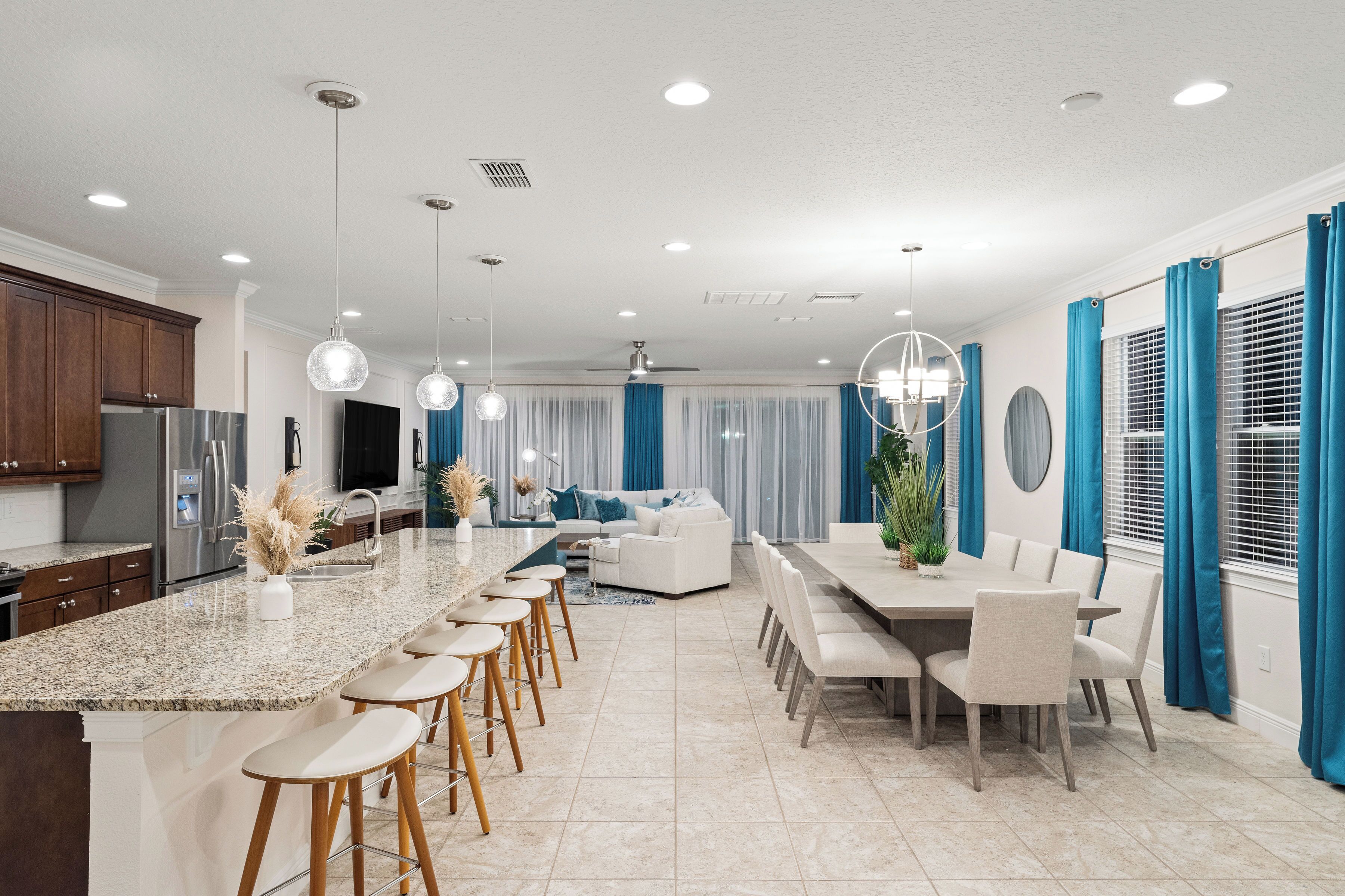 A modern kitchen with a large island, bar stools, and a dining area with a table and chairs.