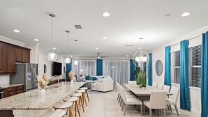 Eine moderne Küche mit einer großen Kochinsel, Barhocker und einem Essbereich mit Tisch und Stühlen.