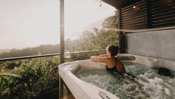 A person relaxing in a hot tub with a view of a lush landscape. - Ananta Dome (Monteverde)