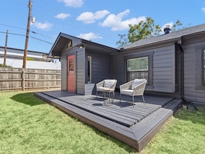 A house with a covered deck, two chairs, and a red door. - Cozy Arlington Bungalow 4/Mins to AT&T Stadium/Globe Life Field (Arlington)