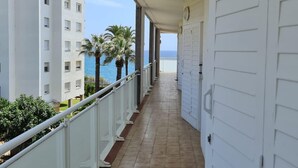 Un couloir donnant sur la mer et les palmiers, qui mène à une porte.
