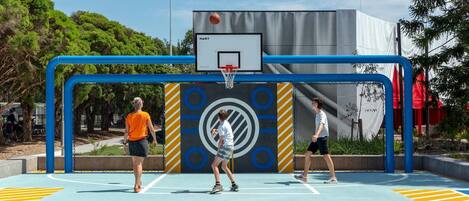 Una cancha de baloncesto exterior con un diseño azul y amarillo, un aro y una red.