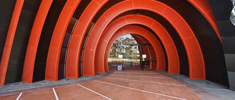 Una estructura en forma de túnel con una serie de arcos, que conduce a un espacio abierto con suelo de baldosas.