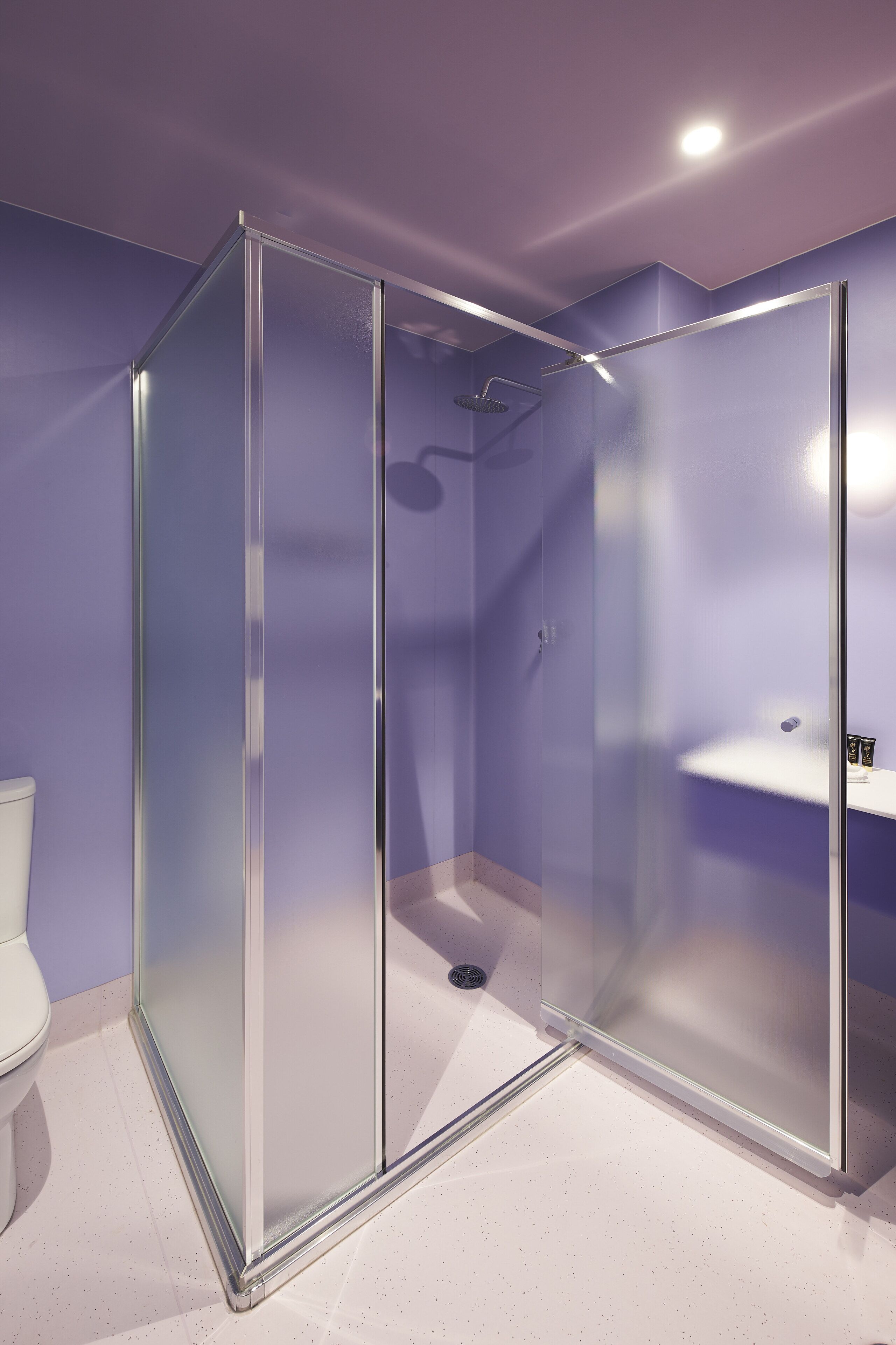 Ein modernes Badezimmer mit einer Glaskabine zur Dusche, einem weißen Waschbecken und einer Toilette.
