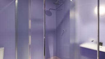Ein modernes Badezimmer mit einer Glaskabine zur Dusche, einem weißen Waschbecken und einer Toilette.