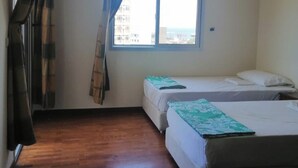 Une chambre avec deux lits, une fenêtre et un plancher en bois.