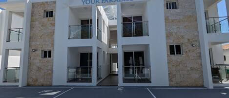 Un hotel de varios pisos llamado "Your Paradise", con un diseño moderno, que cuenta con balcones y ventanas amplias.