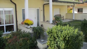 A house with a yellow facade, a front porch with a bench, a potted plant, and a window with a curtain. - Apartment at Sulzbach (Sulzburg)