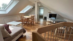 A loft-style bedroom with a sloped ceiling, skylights, a wooden floor, a bed, a desk, and a TV. - Apartment "Dreams im Obergeschoss" with Private Terrace & Wi-Fi (Kötz)