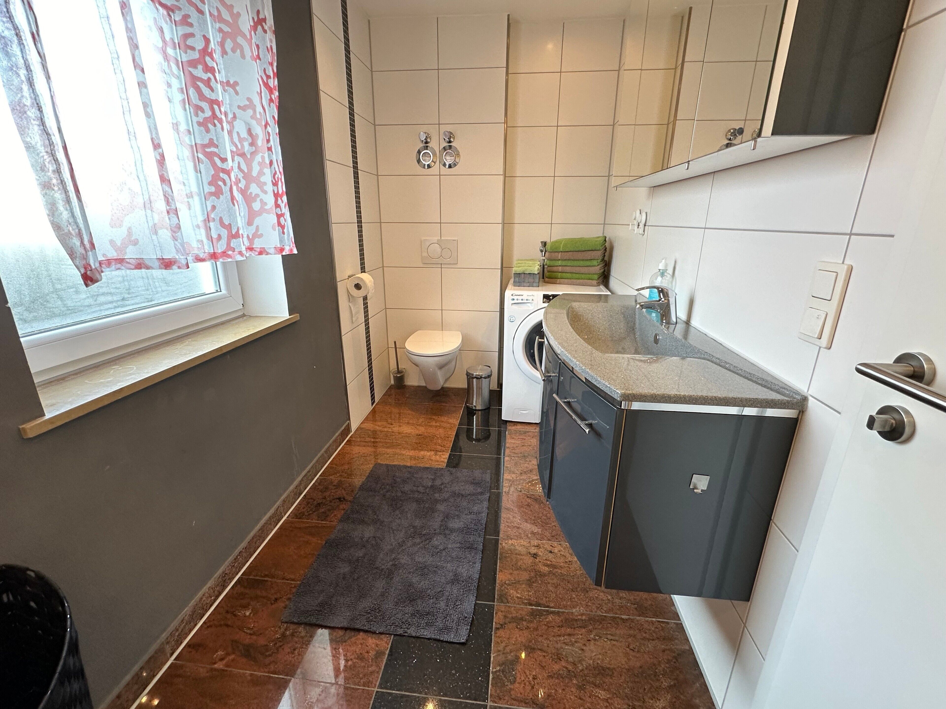 Ein kleines Badezimmer mit Toilette, Waschmaschine und Waschbecken.