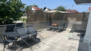 An outdoor patio with a table and chairs, a covered seating area, and a view of the neighborhood. - Apartment "Dreams im Obergeschoss" with Private Terrace & Wi-Fi (Kötz)