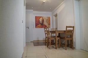 A dining area with a wooden table and chairs, a painting on the wall, and a tiled floor. - Apartment "Dreams im Erdgeschoss" with Wi-Fi (Kötz)