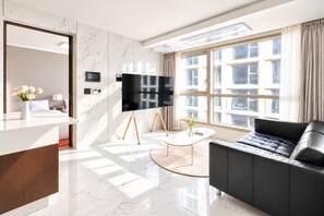 A modern hotel room with a large window, a flat-screen TV, a black leather sofa, and a marble floor. - UH FLAT THE SEOCHO (Seoul)
