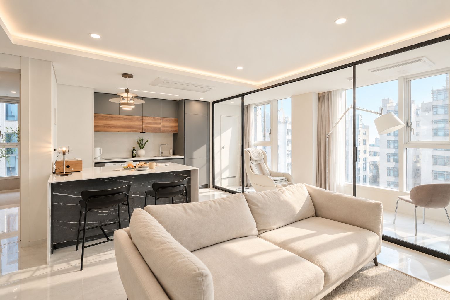 A modern living space with a sofa, a dining area, and a kitchen.
