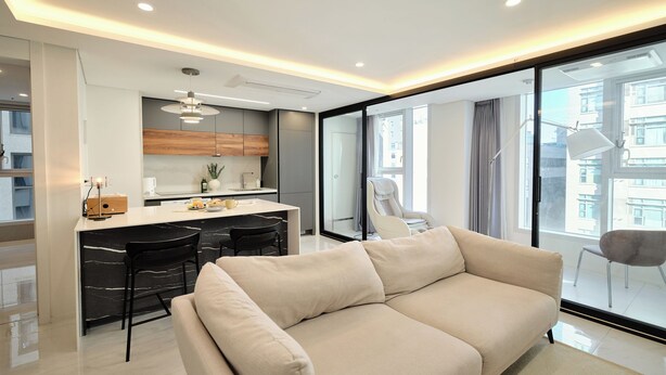 A modern living room with a sofa, a dining area with a kitchen in the background, and large windows offering a view of the city. - UH FLAT THE SEOCHO (Seoul)