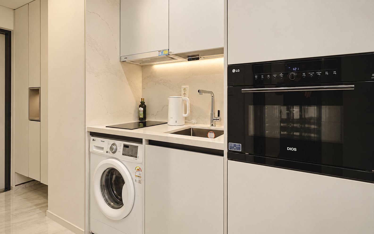 A modern kitchen with a washing machine, a sink, and an oven.
