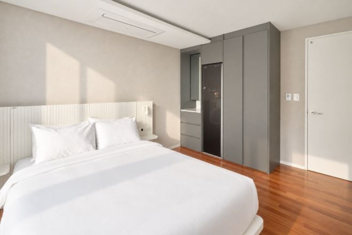A modern hotel room with a large bed, built-in wardrobe, and a door to a bathroom.