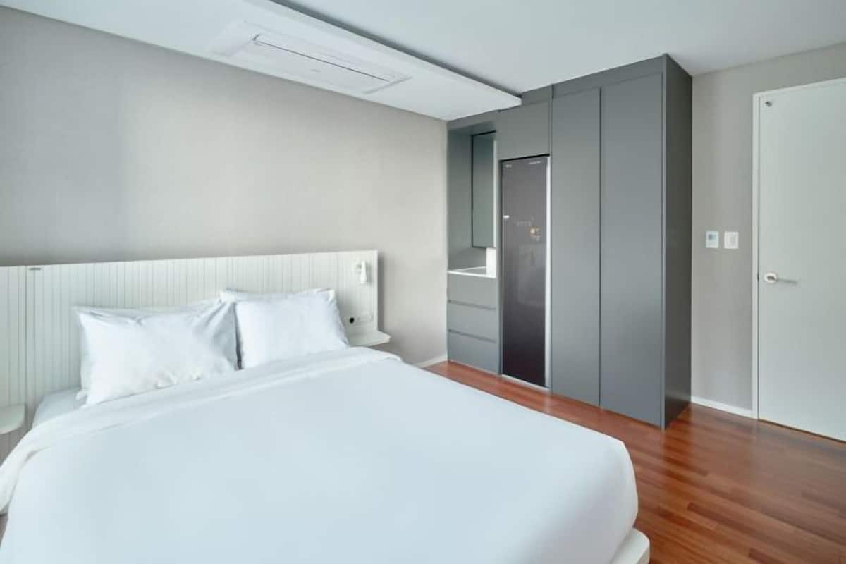 A modern hotel room with a large bed, built-in wardrobe, and a door leading to a bathroom.