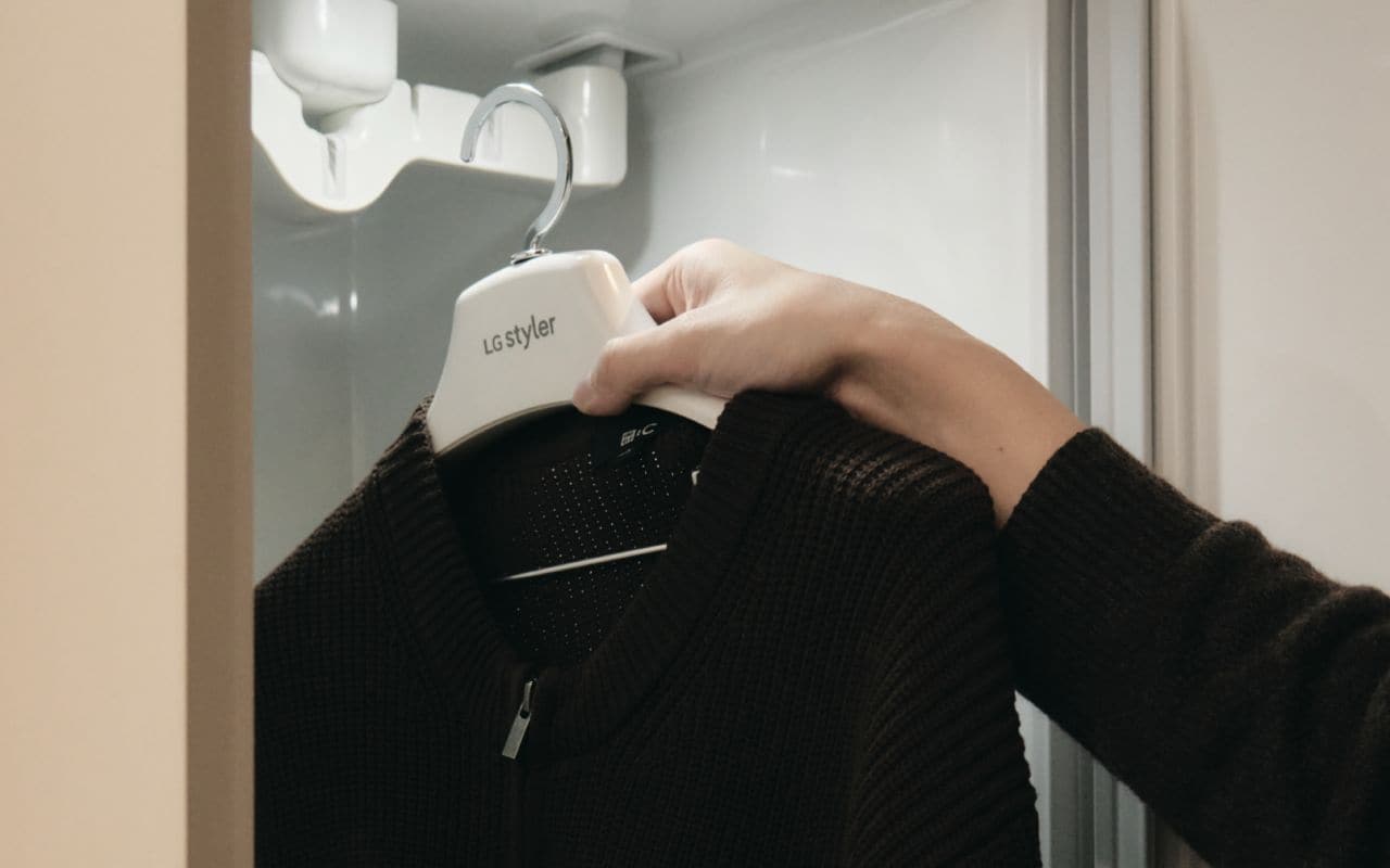 A person holding a garment on an LG Styler hanger.