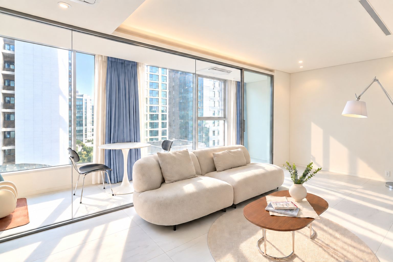 A modern living room with a sofa, a round coffee table, and a dining table with chairs.